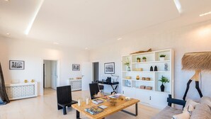 A modern living room with a dining table, black chairs, a white bookshelf, and a lamp. - Borderline Metline (Metline)