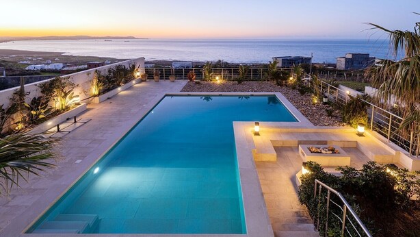 A rectangular swimming pool with steps leading into it, surrounded by a landscaped area with plants and lighting. - Borderline Metline (Metline)