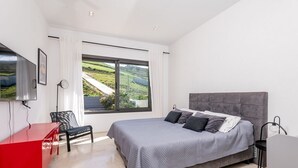 A bedroom with a bed, a desk, a chair, a TV, and a window with a view of a landscape. - Borderline Metline (Metline)