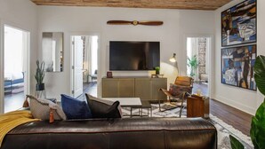Un salon moderne avec un canapé en cuir, un téléviseur à écran plat et un ventilateur de plafond.