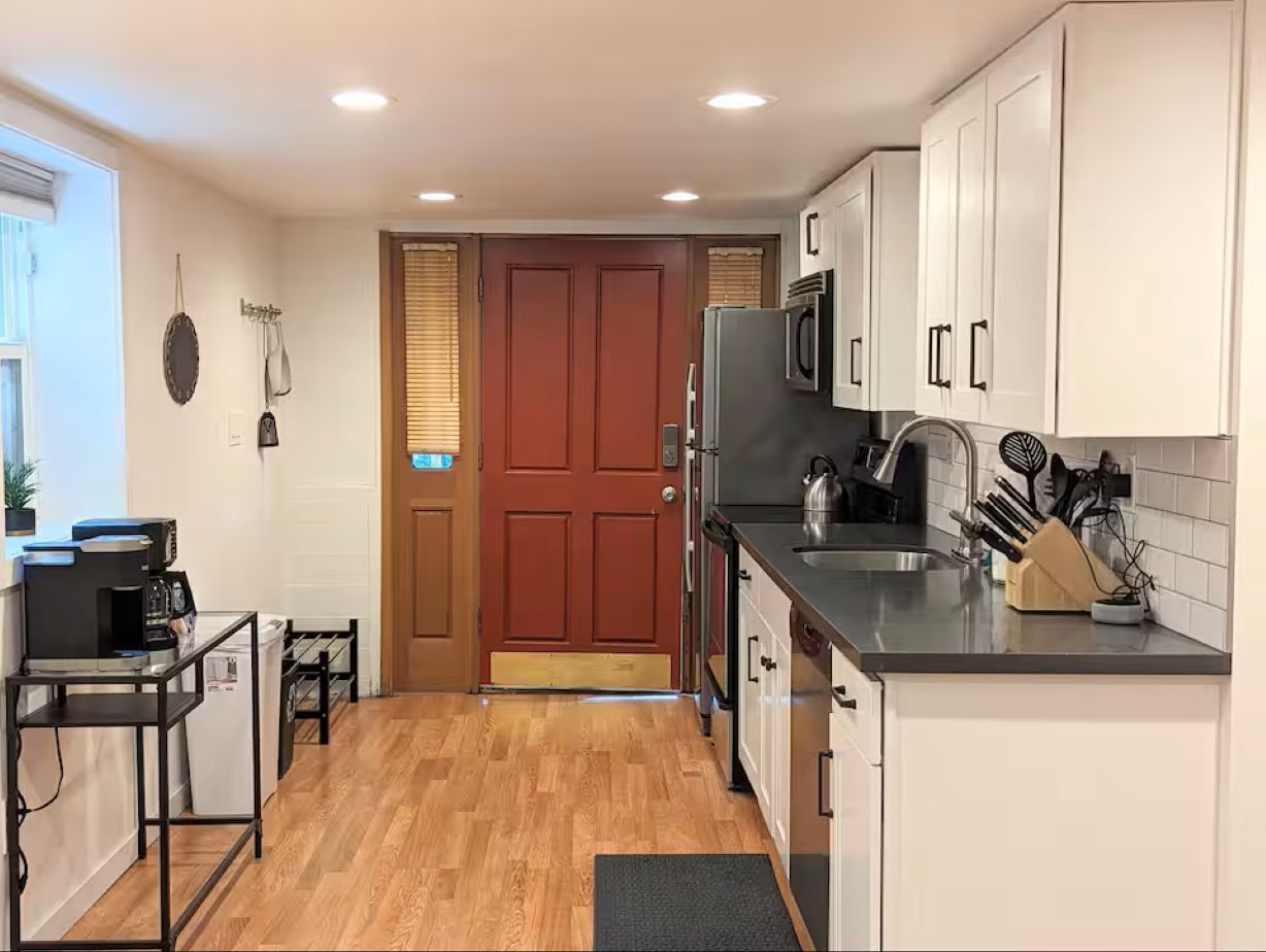 A compact kitchen with a refrigerator, microwave, sink, and a coffee machine.