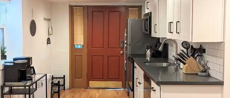 A compact kitchen with a refrigerator, microwave, sink, and a coffee machine.