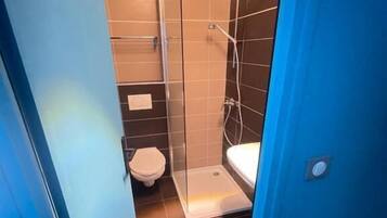 Une salle de bain avec une douche à parois de verre, des toilettes et un lavabo.