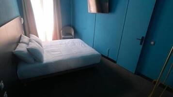 Une pièce comprenant un lit, une chaise, un téléviseur et une armoire.