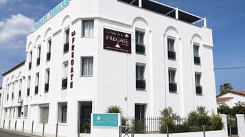 Un bâtiment d’hôtel blanc, doté de nombreux balcons et d’une enseigne indiquant qu’il s’agit d’un hôtel.
