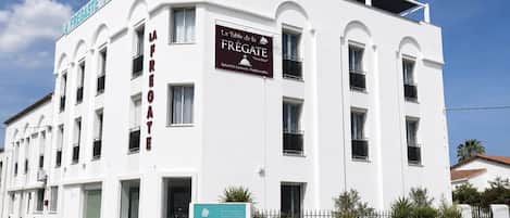 A white hotel building with multiple balconies and a sign indicating it is a hotel.