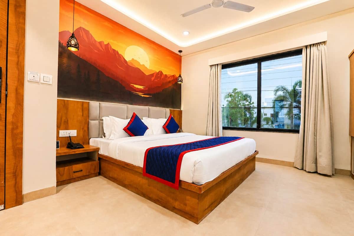 A bedroom with a bed, a nightstand, a wall-mounted lamp, a ceiling fan, and a large window with curtains.