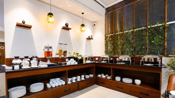 A buffet setup with various dishes and utensils, wooden shelves, and hanging lights. - Bizotel Select Vijay Nagar, Indore (Indore)