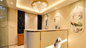 A reception desk with a chandelier, a wall with a peacock illustration, and a marble floor. - Bizotel Select Vijay Nagar, Indore (Indore)