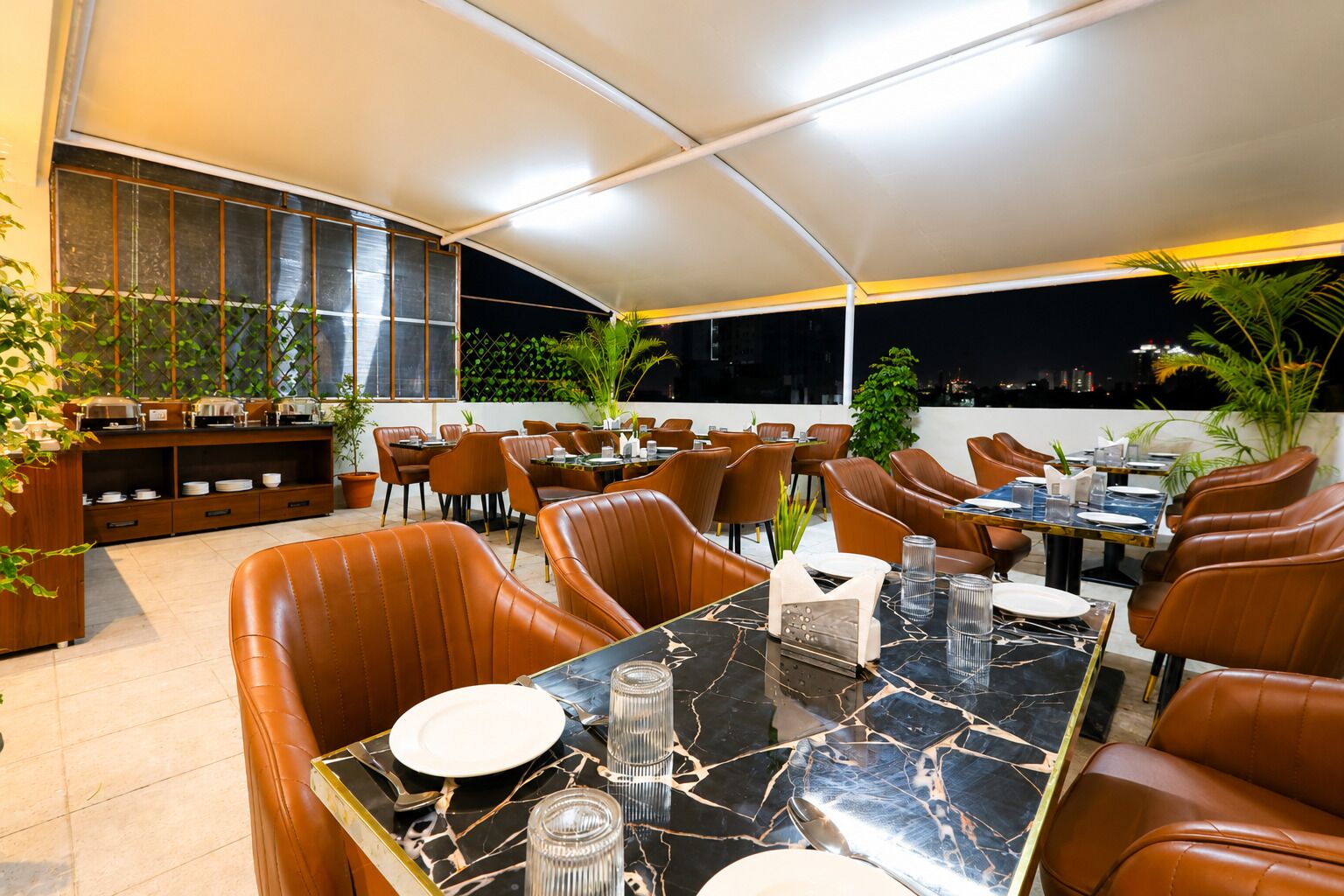 A restaurant with outdoor seating, a marble table, and potted plants.