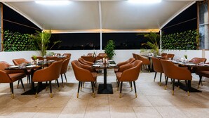 An outdoor dining area with tables and chairs, a white canopy, and a cityscape view at night. - Bizotel Select Vijay Nagar, Indore (Indore)