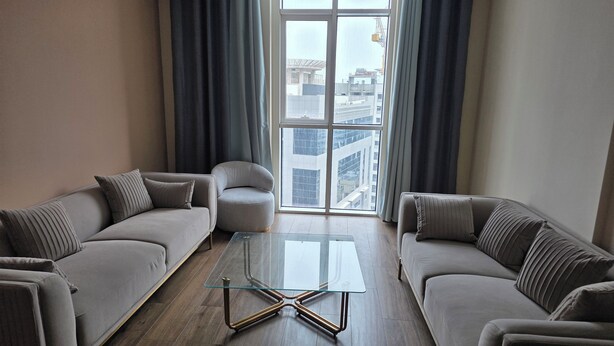 A modern living room with two sofas, a glass coffee table, and a view of a cityscape through large windows.