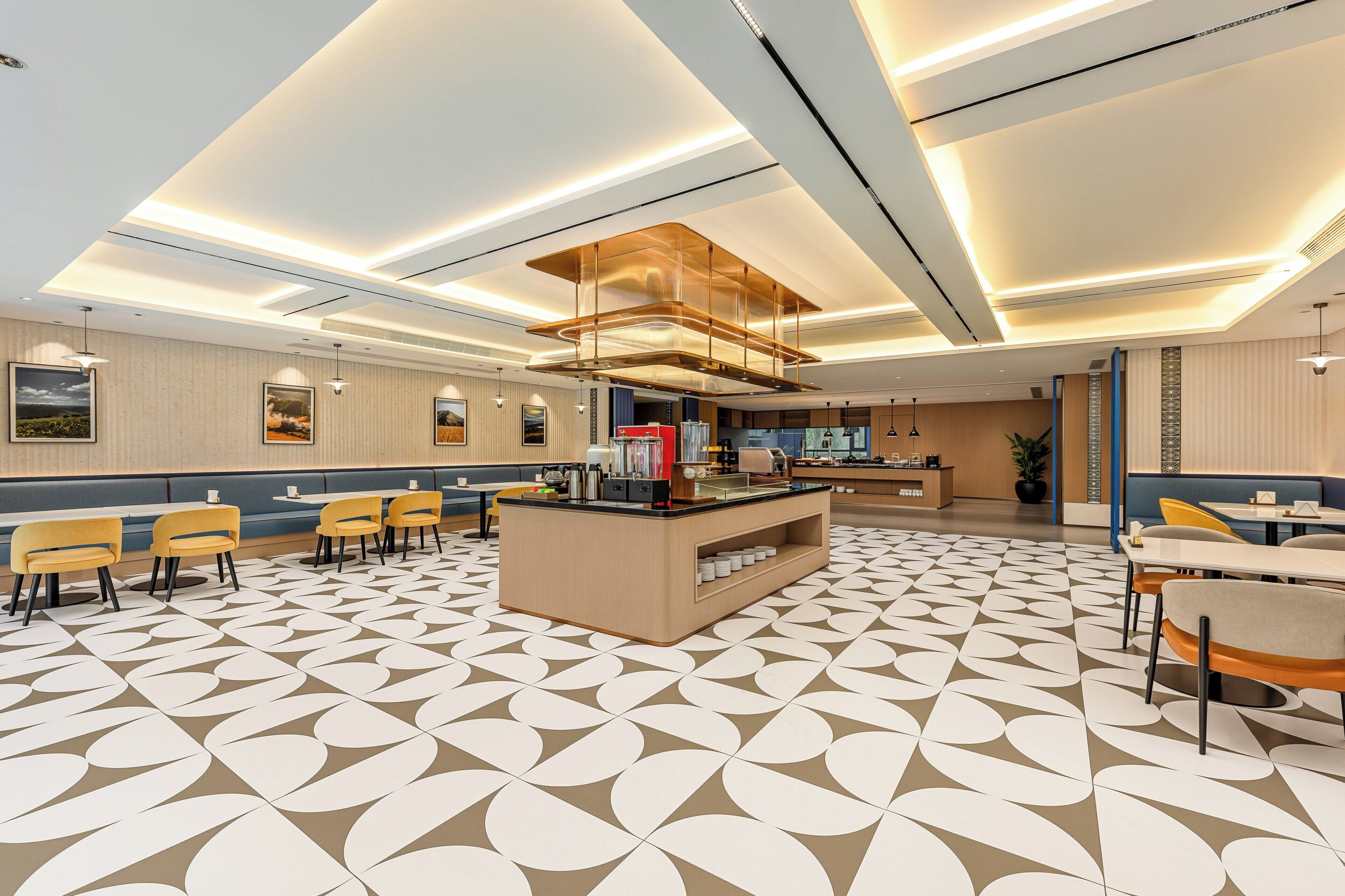 A modern hotel lobby with a central reception desk, seating areas, and a patterned floor.