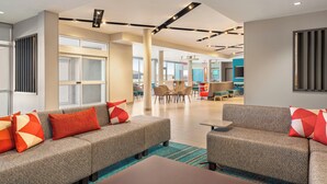 A modern lounge area with sofas, a coffee table, and a dining area with chairs and tables. - avid Hotel Redding by IHG (Redding)