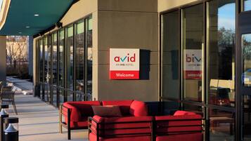 An exterior of a hotel with a red sofa, a 'Welcome' sign, and glass doors.