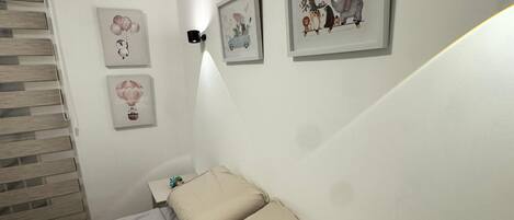 A bedroom with a bed, a nightstand, and three framed pictures on the wall.