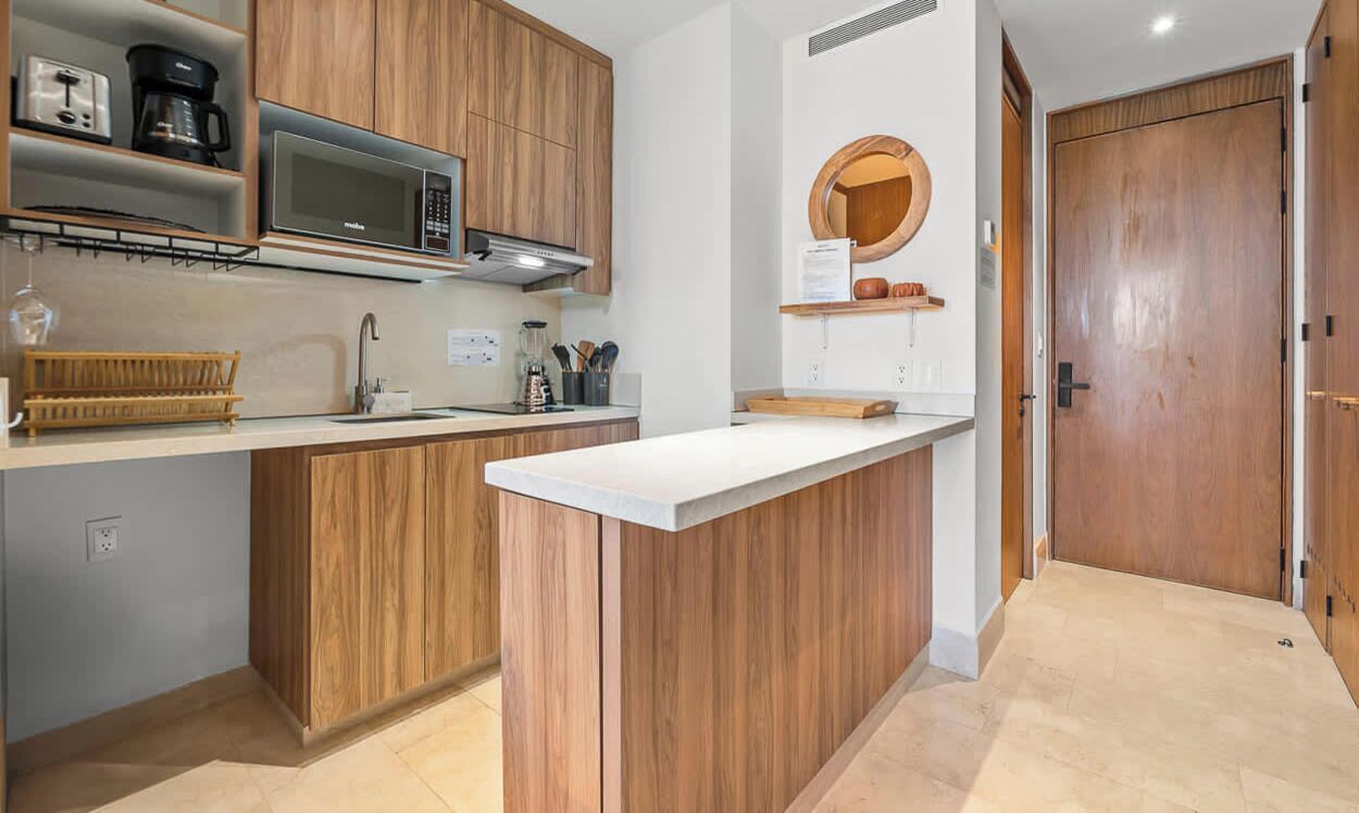 A modern kitchen with wooden cabinets, a microwave, a coffee maker, and a sink.