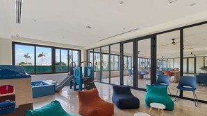 A spacious indoor area with large windows, a slide, and various seating options. - Zantamar 104B: Beachfront Studio Steps to Ocean (Cruz de Huanacaxtle)