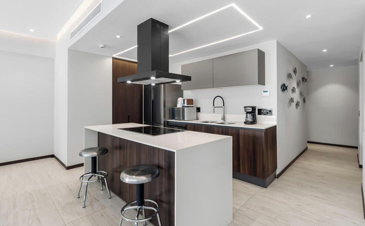 Une cuisine moderne dotée d’un îlot central, de tabourets de bar, d’une cuisinière encastrée et d’une machine à café.