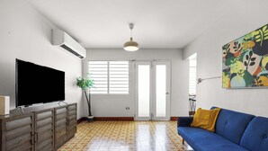 A living room with a television, sofa, and patterned floor tiles. - T-Mobile District | 3BR Apartment | San Juan (San Juan)