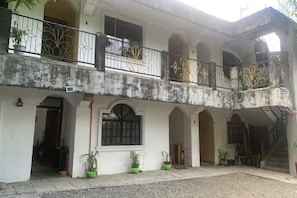A two-story building with balconies, a staircase, and potted plants.