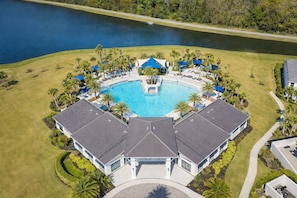 An aerial view of a resort with a central swimming pool, surrounded by palm trees and a body of water. - 10BR Resort Villa, 8 Bath, Sleeps 22, Pool, Near Disney (Kissimmee)
