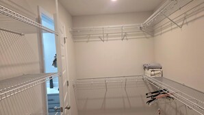 Ein begehbarer Kleiderschrank mit Metallregalen, einer Tür und einer Deckenleuchte.