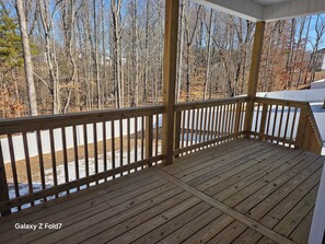 A wooden deck with a railing, surrounded by trees and a white fence. - The Boulders Subdivision is New, Peaceful & Serene. (Clarksville)