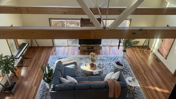 A high-ceilinged room with a wooden beam structure, a sofa, a small round table, a potted plant, and a keyboard. - Delightful 4-bedroom Plus House in  East Chatham with Pool, Sauna and AC (East Chatham)
