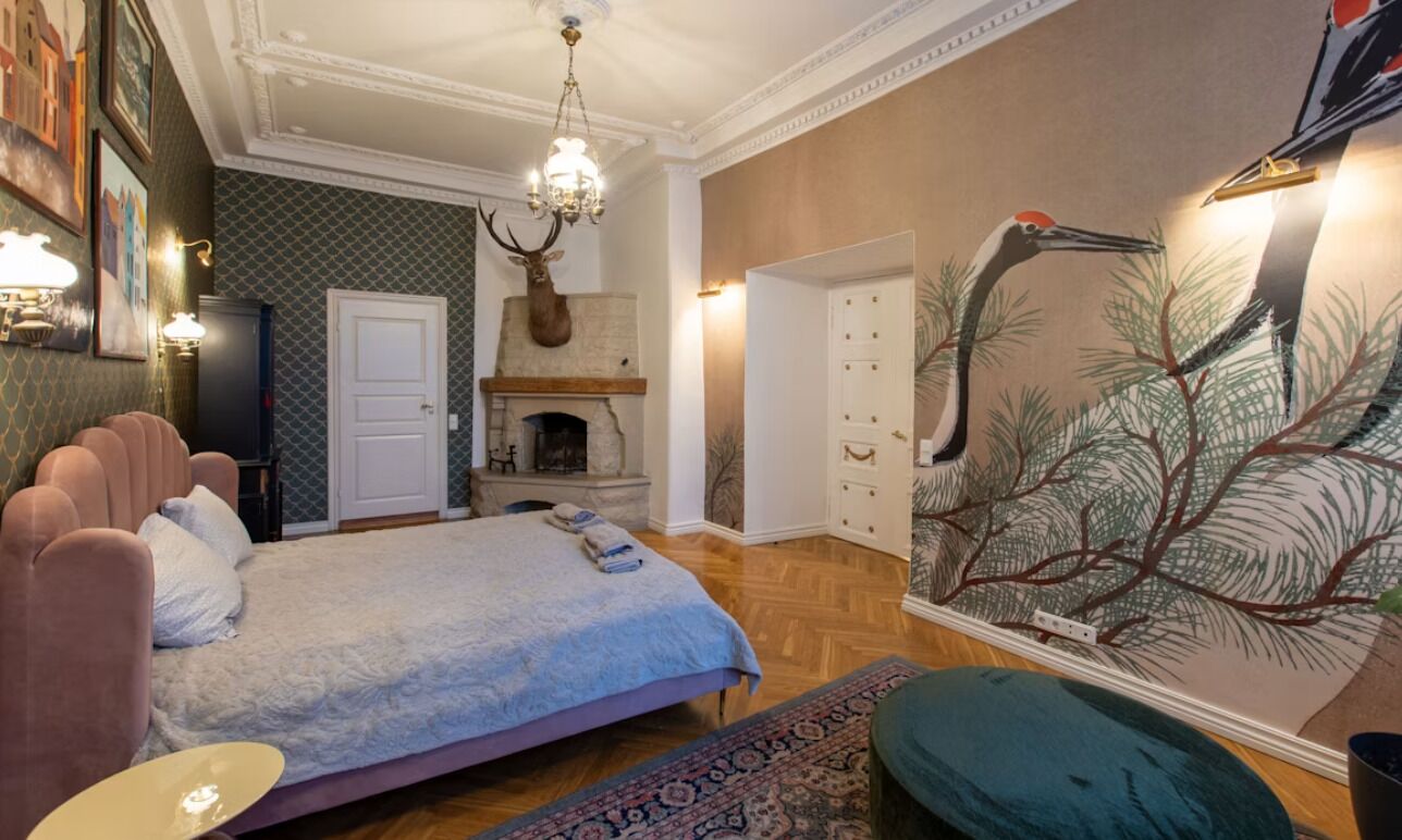 Un dormitorio con cama, chimenea, candelabro y un mural en la pared.