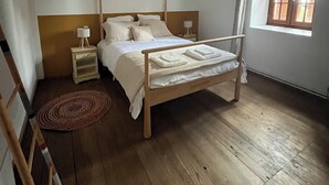 A bedroom with a wooden bed, a nightstand, a lamp, and a window with curtains. - Family house 14pers, air conditioning, swimming pool and wifi (Laplume)