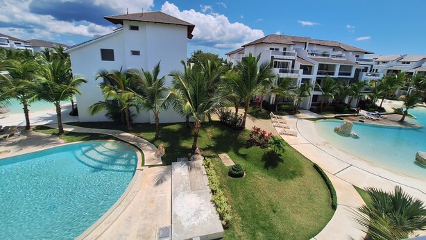 A resort with a swimming pool, palm trees, and multiple buildings. - Exclusive penthouse in Dominicus with 5 pools in a tropical setting (Dominicus)