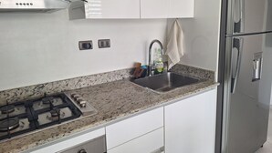 A kitchen with a stainless steel refrigerator, a gas stove, a sink, and white cabinetry. - Exclusive penthouse in Dominicus with 5 pools in a tropical setting (Dominicus)