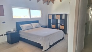 A bedroom with a bed, nightstands, a headboard, a window, and a built-in shelving unit. - Exclusive penthouse in Dominicus with 5 pools in a tropical setting (Dominicus)