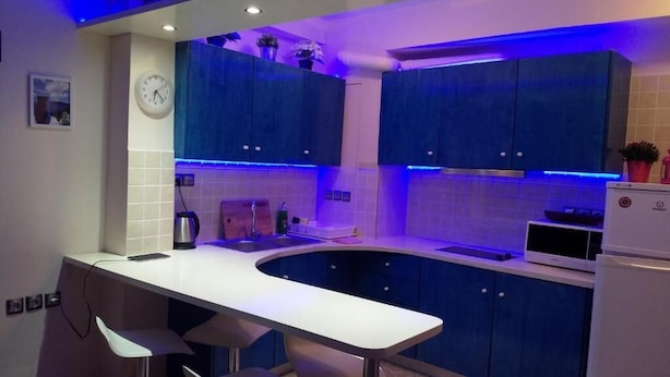 A modern kitchen with blue cabinets, a white countertop, and bar stools. - Cozy apart Kontouli - Perfect studio apartment-5 min walk from Acropolis (Athina)