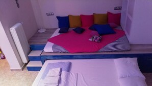 A bed with a pink and white bedspread, a blue and white striped pillow, and a white blanket. - Cozy apart Kontouli - Perfect studio apartment-5 min walk from Acropolis (Athina)