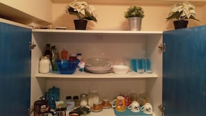A kitchen pantry with shelves containing various kitchen items, including jars, bottles, and dishes. - Cozy apart Kontouli - Perfect studio apartment-5 min walk from Acropolis (Athina)