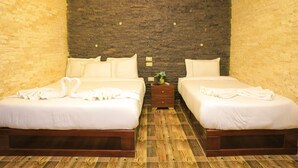 A double room with two beds, a wooden floor, a brick wall, and a small nightstand with a lamp. - Spacious 9-bedroom hotel in charming Giza Governorate with AC (Giza Governorate)