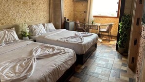 A room with two beds, a small table, a chair, a potted plant, and a view of the outside. - Spacious 9-bedroom hotel in charming Giza Governorate with AC (Giza Governorate)