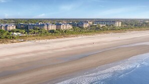 Um hotel à beira-mar com vários edifícios, uma praia de areia e vista para o oceano.