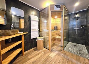 Ein modernes Badezimmer mit einem Holzkosmetikschrank, einem großen Spiegel, einer Sauna und einer Duschkabine.