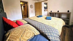 A bedroom with a bed, a wooden door, a mirror, and a shelf with items. - 2P gîte with sauna on the Route des Vins near Colmar (Bergheim)