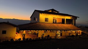 A two-story house with a tiled roof, a balcony, and string lights.