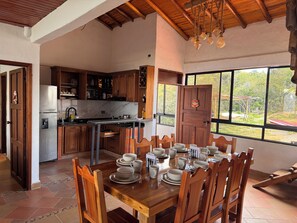 A spacious kitchen with wooden cabinets, a stainless steel refrigerator, and a dining area with a wooden table set for four.