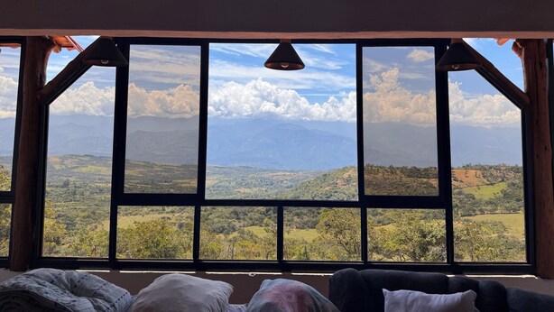 A room with a large window offering a view of a mountainous landscape.