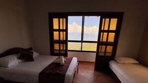 A bedroom with a bed, a chair, a window with a view, and a door.