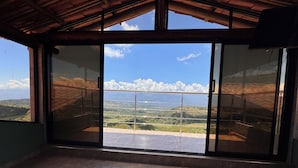 A room with a large sliding glass door leading to a balcony with a view of a mountainous landscape.