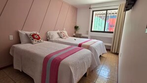 Un dormitorio con dos camas, una ventana con vistas y una mesita de noche pequeña.