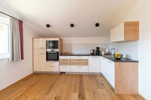 A modern kitchen with white cabinetry, a built-in oven, a microwave, and a coffee maker. - Apartment Sodalit in Haus Alpenblick (St. Wolfgang)