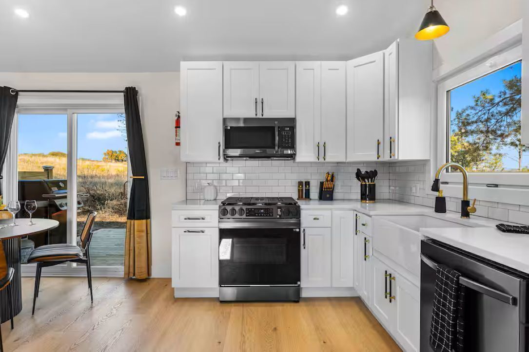 A modern kitchen with white cabinets, a black stove, and a microwave.